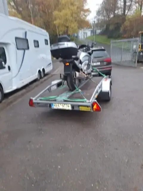 Motocykl na přívěsu u obytného vozu